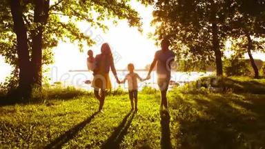 幸福的一家人走在海边。 农村的田野和树木。 日落或日出的暖色。 有爱心的父母